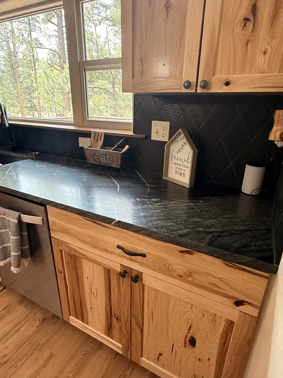 Black stone countertop run beneath a kitchen window