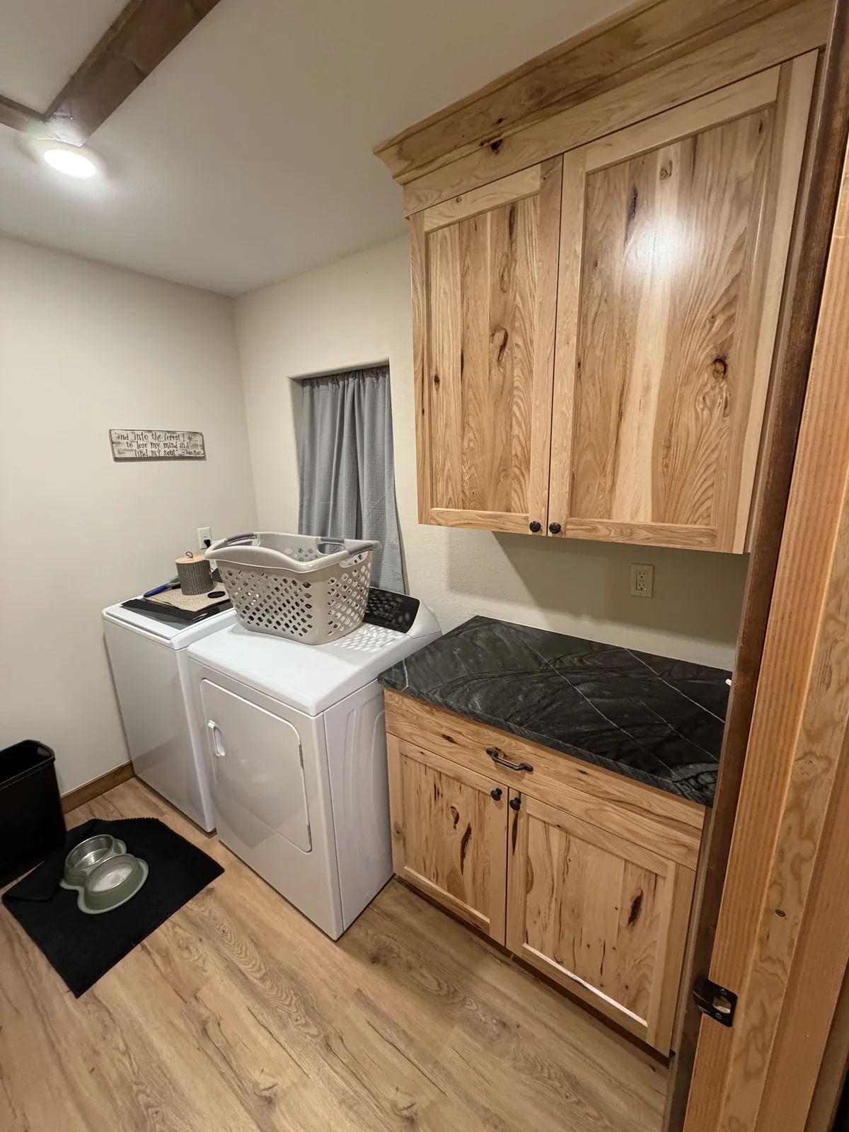 Laundry counter and cabinet area with black stone surface