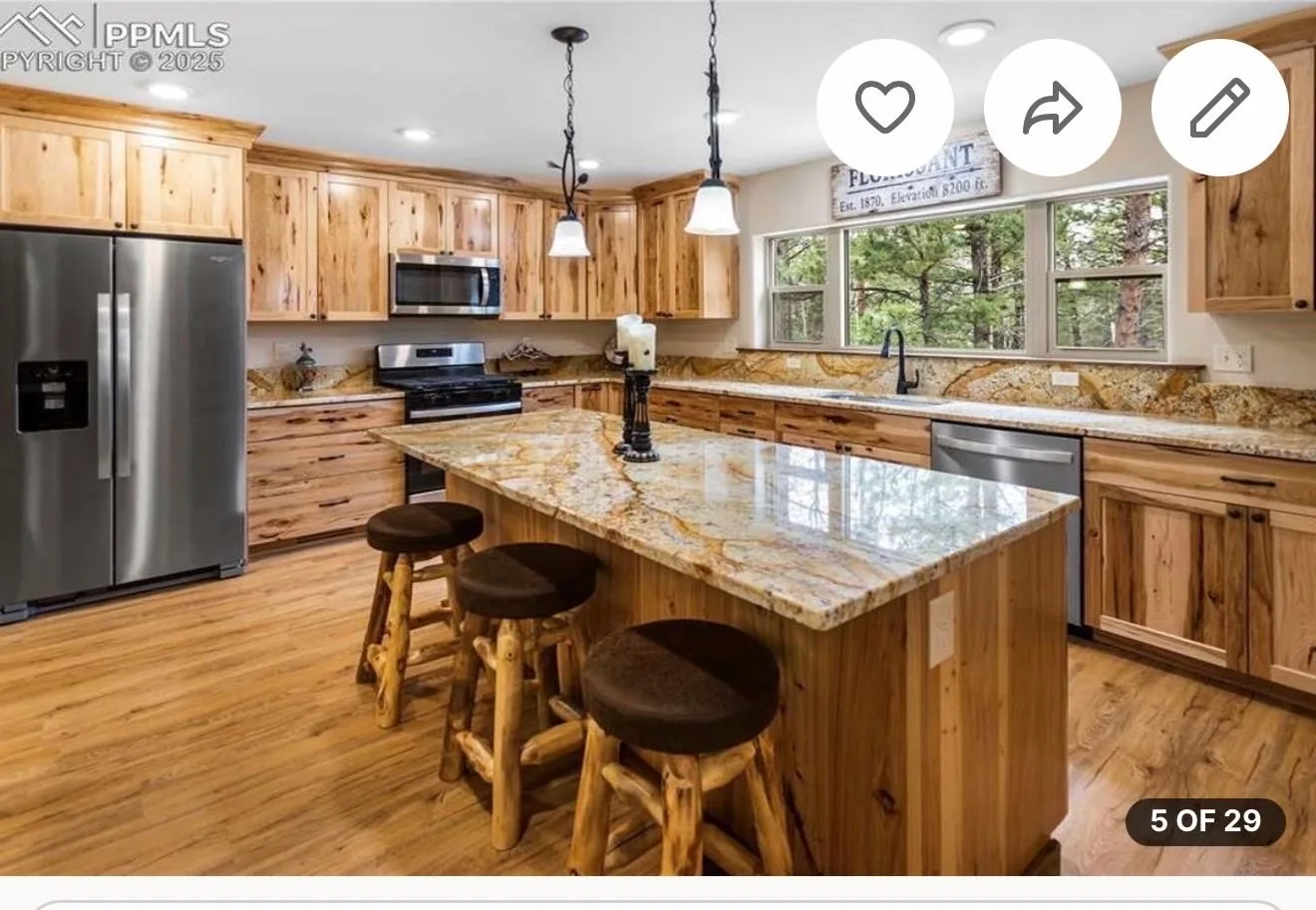 Wide view of rustic kitchen with stone island and wood cabinet backsplash area