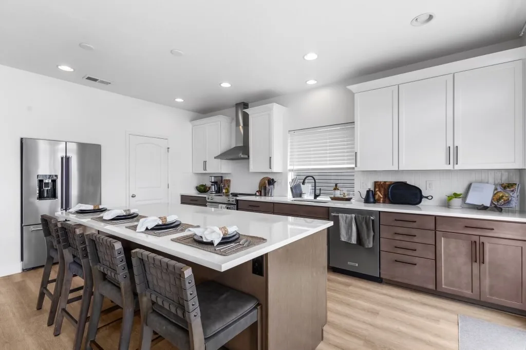 Finished kitchen remodel with island seating, white counters, and two-tone cabinets
