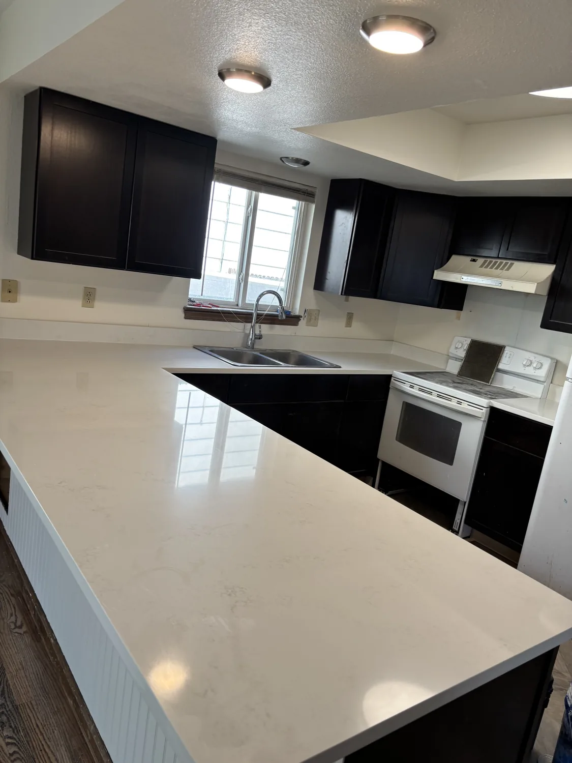Finished kitchen remodel with white countertops and dark cabinets