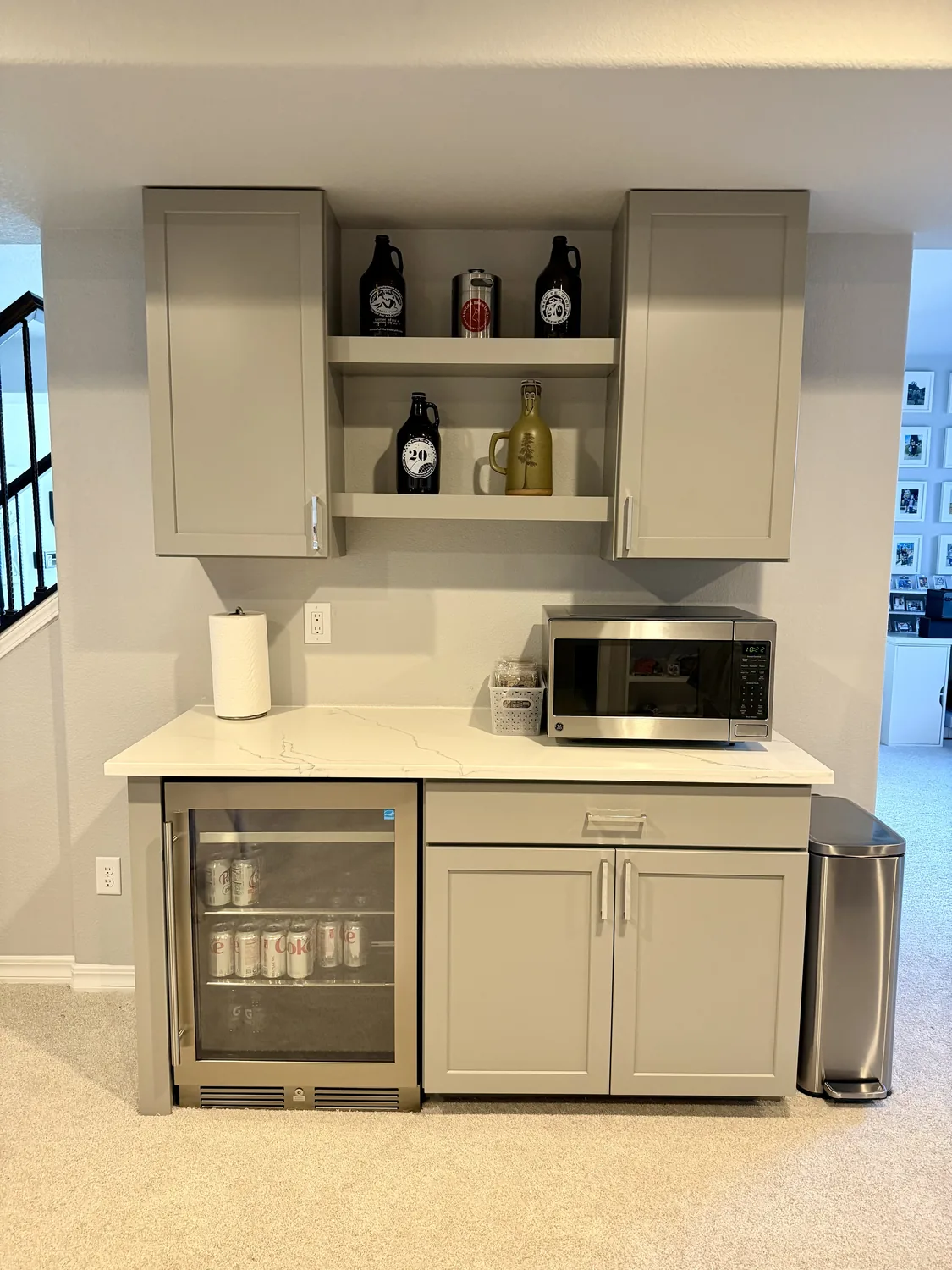 Finished built-in bar area with cabinets, shelves, stone surface, and beverage cooler