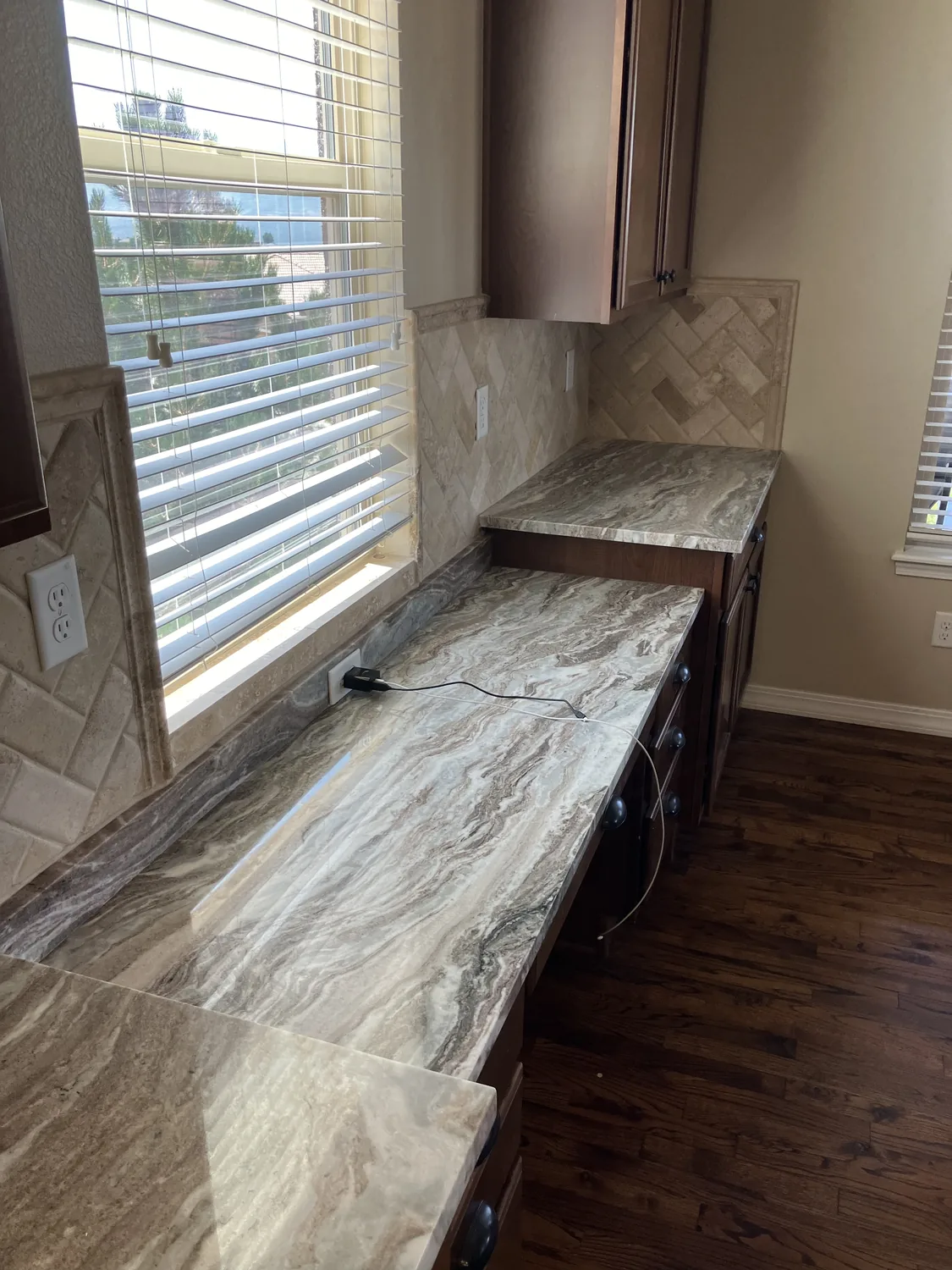 Long stone countertop run beneath a kitchen window